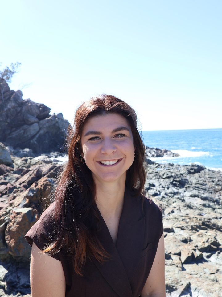 Nadine Odermatt lächelt in die Kamera, im Hintergrund Felsen und Meer